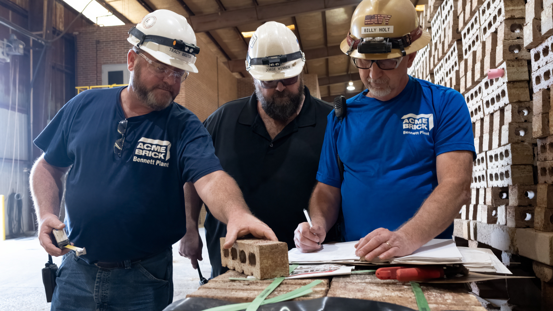 Three Acme Brick workers in blue, Acme Brick branded shirts working